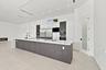 Contemporary kitchen featuring a large waterfall-edge island with dark wood-finish cabinetry, stainless steel appliances including a built-in refriger