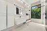 Spa-inspired primary bathroom featuring a floating white vanity with integrated sink, frameless glass shower enclosure, linear ceiling lighting, and l