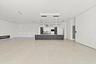 Expansive open-concept space featuring light wood-finish flooring, recessed ceiling lighting, and a contemporary dark-finished bar counter with integr