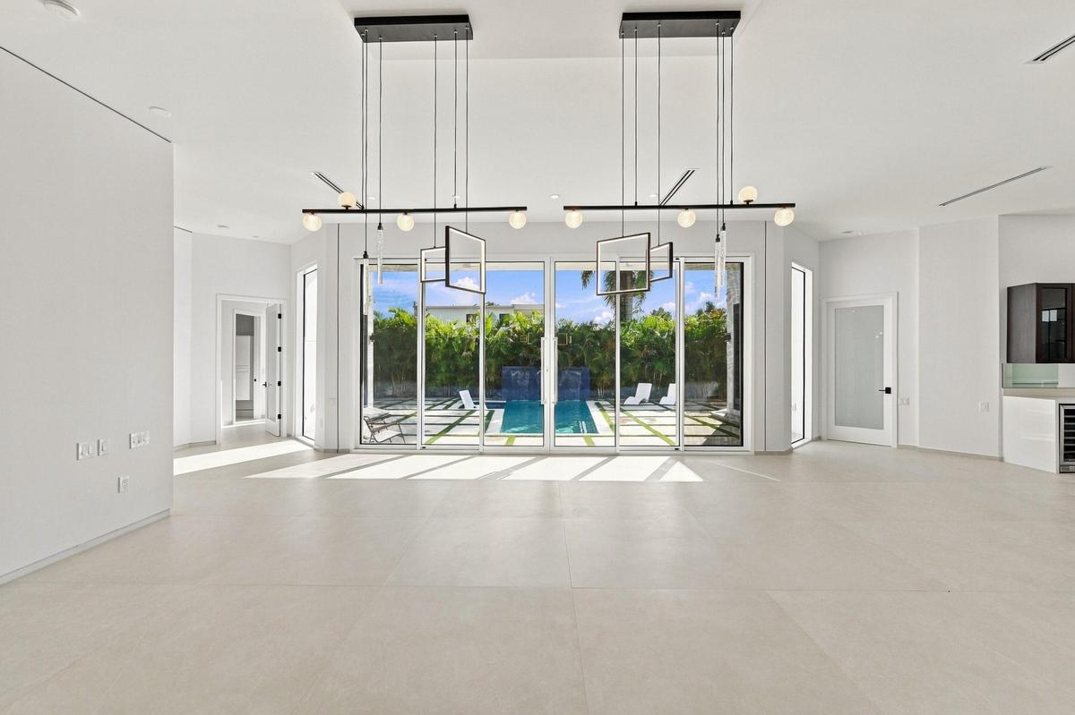Expansive open-concept room with light-toned flooring and multiple floor-to-ceiling glass sliding doors