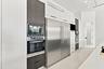 Contemporary kitchen featuring stainless steel side-by-side refrigerator with dual doors, built-in wall ovens with black glass fronts, integrated micr