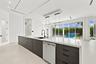 Chef's kitchen featuring a substantial island with wood-finish cabinetry, white quartz countertops, integrated dishwasher, and matte black faucet with