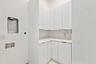 Efficient kitchenette featuring white cabinetry, light countertops, and a single-basin sink with chrome faucet