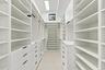 Custom closet system featuring extensive shelving, built-in drawers with modern hardware, integrated hanging rods, and a task ladder