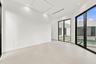 Bright, open interior space featuring polished concrete flooring, floor-to-ceiling glass doors with black aluminum framing, and recessed ceiling light