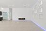 Sophisticated open-concept living space featuring light-toned polished concrete flooring, expansive white walls with architectural detail panels, rece