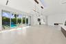 Expansive sliding glass doors, contemporary linear fireplace, recessed lighting, sleek kitchen island, and a custom built-in bar
