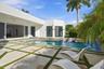 Modern exterior architecture featuring a swimming pool, integrated water feature, paver patio with turf accents, and large sliding glass doors