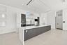 Modern kitchen featuring a large waterfall-edge island with wood-finish cabinetry, stainless steel appliances including a built-in refrigerator and wa