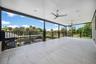 Expansive covered balcony featuring large-format tile flooring, sleek black railings, and multiple ceiling fans with recessed lighting