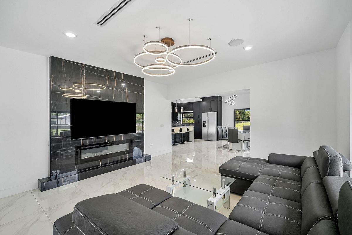 Porcelain tile flooring, built-in electric fireplace, wall-mounted television, recessed lighting, and contemporary circular chandelier