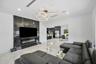 Porcelain tile flooring, built-in electric fireplace, wall-mounted television, recessed lighting, and contemporary circular chandelier