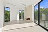 Modern living space featuring polished concrete flooring, floor-to-ceiling glass sliding doors with black metal framing, recessed ceiling lighting, an