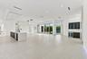 Expansive open-concept living space featuring polished light-toned flooring throughout, abundant natural light from multiple glass sliding doors and w