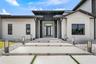 Modern stucco exterior featuring a tiered concrete entry, a dark-framed glass paneled front door, and integrated outdoor lighting