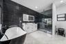 Freestanding soaking tub, dual vanity with undermount sinks, walk-in shower with glass enclosure, large format black tile accent wall, and white tile 