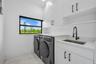 White cabinetry with black hardware, stone countertops, undermount sink with a matte black faucet, and white tile flooring
