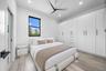 Expansive built-in wardrobe system with ample storage, contemporary ceiling fan, recessed lighting, wood-finish flooring, and multiple windows