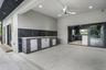 Covered outdoor living space featuring an integrated outdoor kitchen, contemporary ceiling fan, recessed lighting, and large format floor tiling