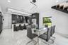 Modern kitchen featuring dark cabinetry, stainless steel appliances, a breakfast bar, and white tile flooring