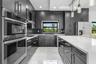 Kitchen with dark cabinetry, white countertops, built-in double oven, stainless steel appliances, and sleek pendant lighting