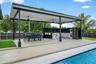 Covered outdoor kitchen featuring a built-in sink, ample counter space, and integrated appliances