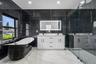 Freestanding soaking tub, dual vanity with undermount sinks, walk-in shower with glass enclosure, large format wall tiling, and recessed lighting
