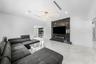 Open-concept living space with large format tile flooring, a dark accent wall with an integrated electric fireplace, and a contemporary ceiling fixtur