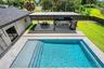 Rectangular swimming pool with integrated steps, surrounded by light-toned tile decking