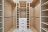 Custom closet system featuring natural wood-finish backing