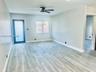 Light-toned wood-finish flooring, white walls, black ceiling fan, and a door with frosted glass panel