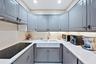 U-shaped kitchen featuring grey shaker cabinetry, white countertops, a flat-top electric range, and an apron-front sink with a gooseneck faucet