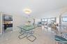 Expansive open-concept living area showcasing polished light-stone flooring, floor-to-ceiling windows with panoramic outlooks, recessed ceiling lighti