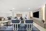 Recessed ceiling lighting, light wood-finish flooring, built-in entertainment unit with integrated lighting, a stone-finish accent wall, and a column-