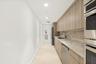 Integrated kitchen area featuring wood-finish cabinetry, stainless steel appliances, a matte black faucet, and stone countertops with a matching backs