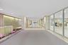Recessed lighting illuminates a long hallway with full-height glass panels
