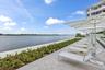 Waterfront property featuring a paver patio with landscaping, lounge chairs, and shade umbrellas
