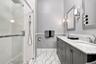 Modern bath w/dual sink vanity with stone countertop, glass-enclosed shower and marble floors