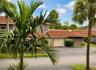 Stucco exterior featuring a terracotta tile roof, attached garage, and mature landscaping
