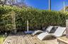 Wood-plank decking with an outdoor shower and lush privacy hedging