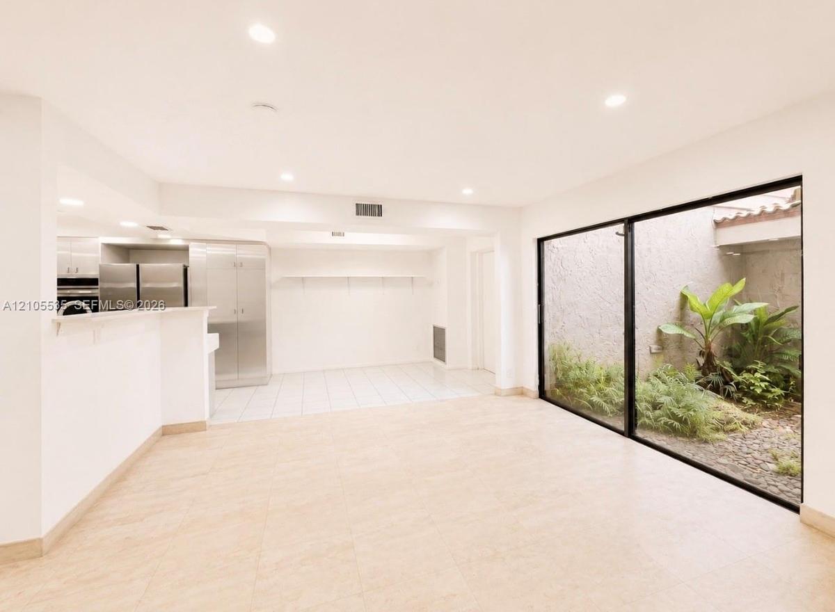 Recessed lighting, tile flooring, full-height glass panels, and an enclosed courtyard with established plantings