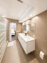 Dual floating vanities with integrated sinks, recessed lighting, glass block wall, and large wall-mounted mirror