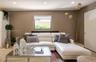 Recessed ceiling lighting, a single window with blinds, and light-toned walls create an inviting living space
