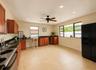Kitchen featuring tile flooring, wood cabinetry, dark countertops, a stainless steel range, and a black refrigerator