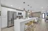 Modern kitchen featuring white cabinetry, stainless steel appliances, a center island with sink, and pendant lighting