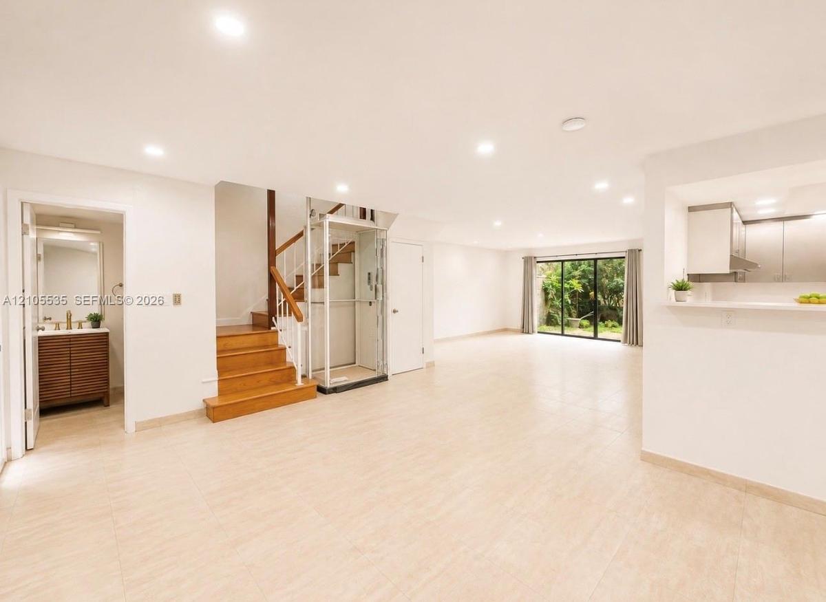 Recessed lighting, wood staircase, clear glass elevator, tiled flooring, and sliding glass doors