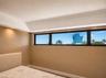 Recessed ceiling lighting, soffit lighting, window wall with black frames, and a prominent distant building