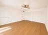 Wood-finish flooring, ceiling fan with integrated lighting, and multiple louvered bifold closet doors
