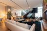 Expansive open-concept living area with wood-finish flooring, high ceilings, built-in shelving, and a prominent staircase with dark wood-finish treads