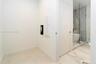White interior walls, light-toned tile flooring, and a glass-enclosed shower with a marble-patterned tile surround